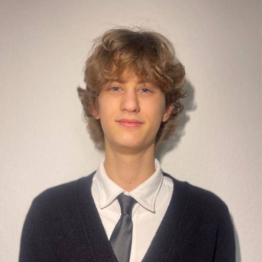 Portrait of Nicklas Plugin wearing a white shirt, tie, and dark cardigan.